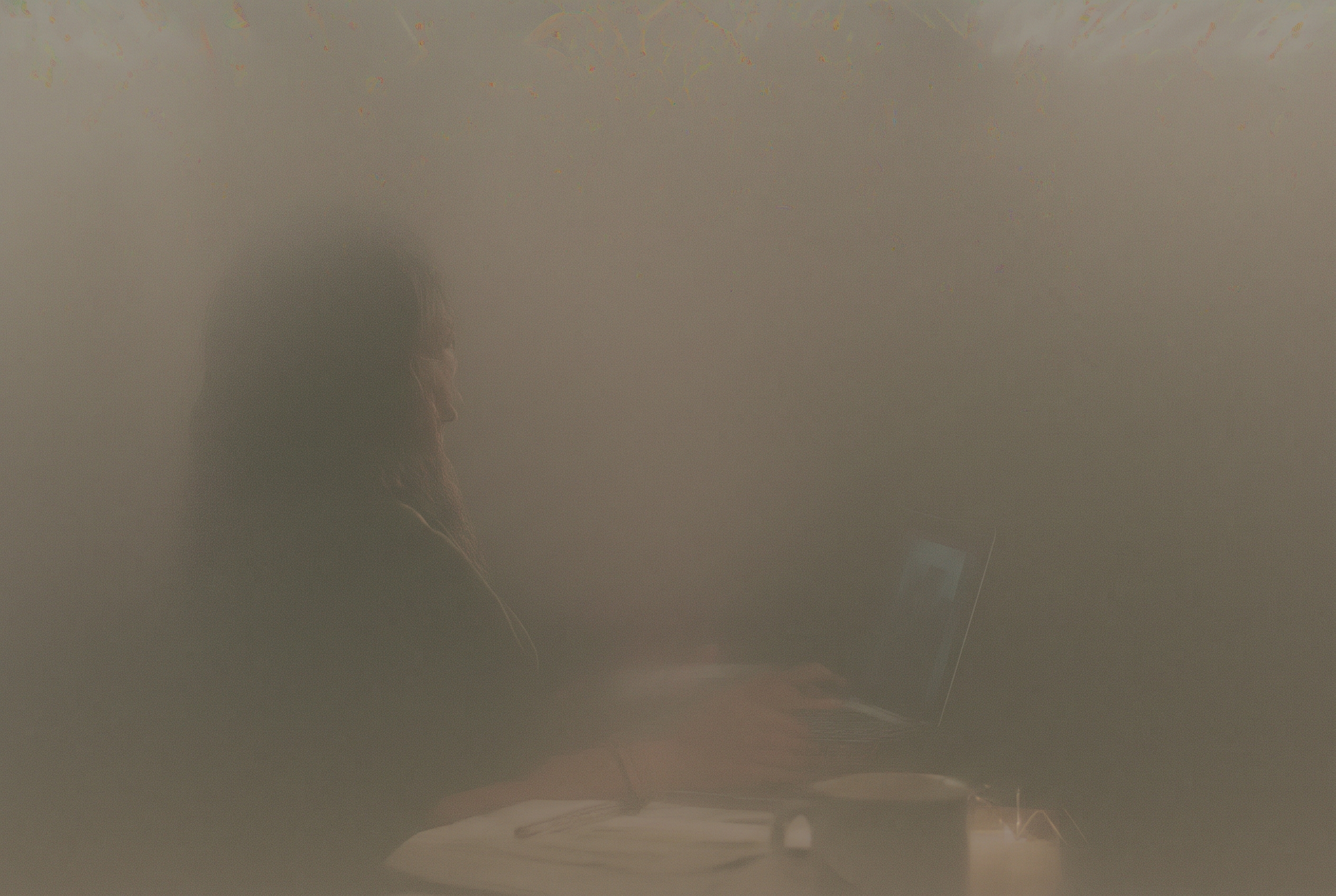 New entrepreneur setting up an online store on a laptop at a kitchen table with a coffee mug and notebook beside her